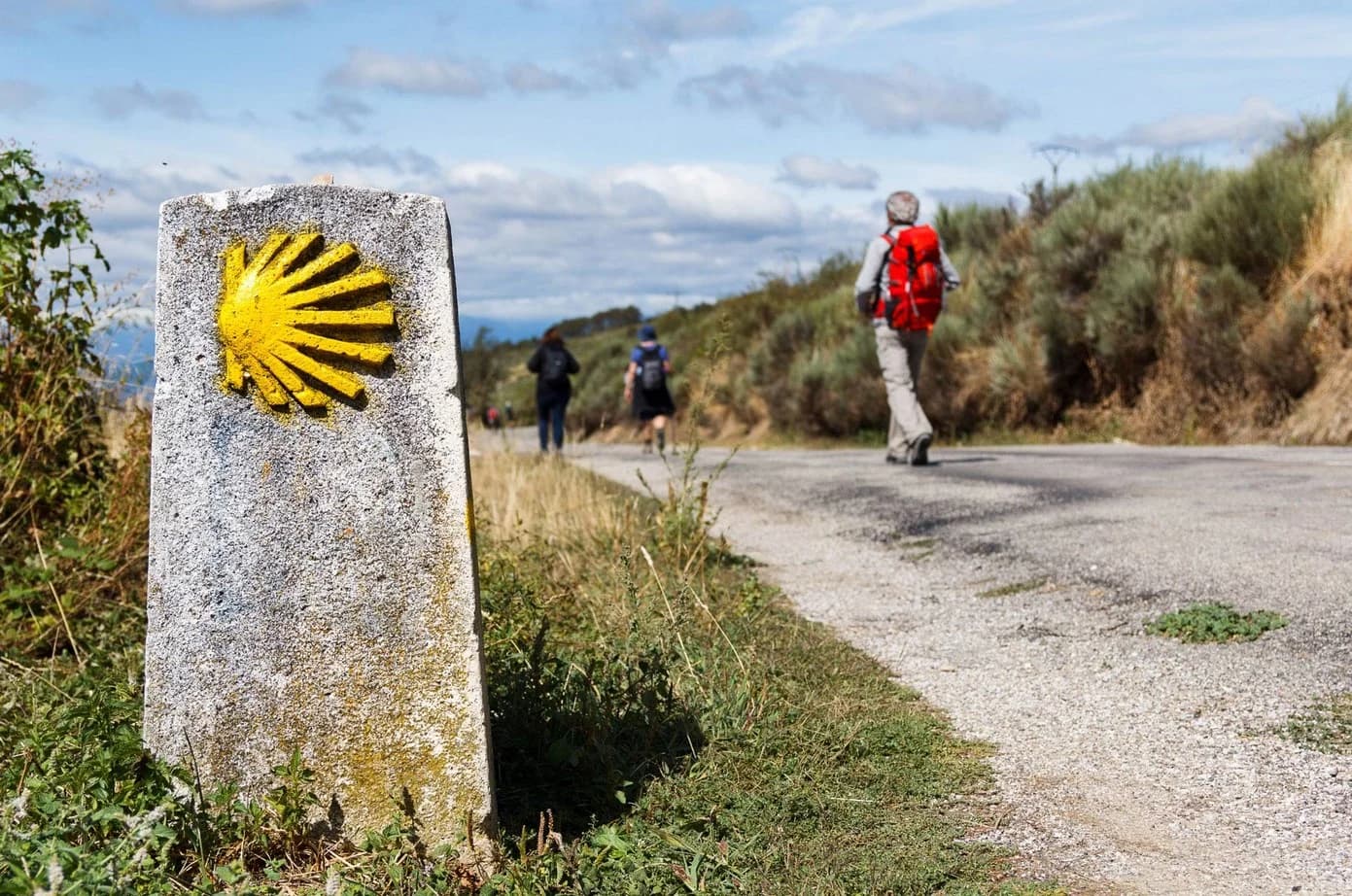 Peregrinos caminando por el histórico Camino de Santiago con mochilas y bastones de peregrino